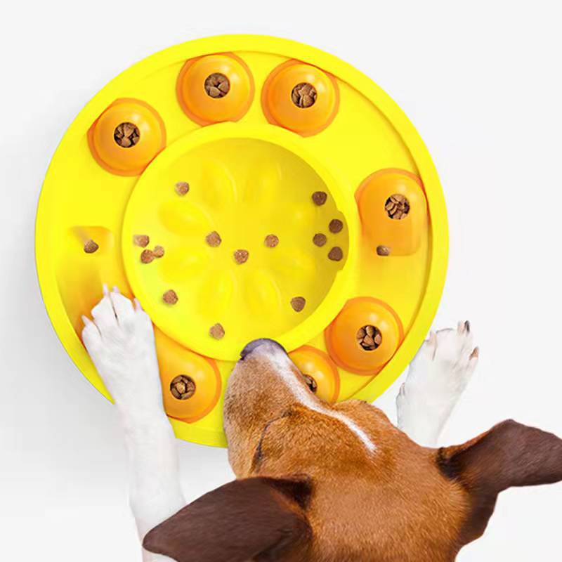 Dog interacting with a yellow puzzle toy filled with treats on a white background
