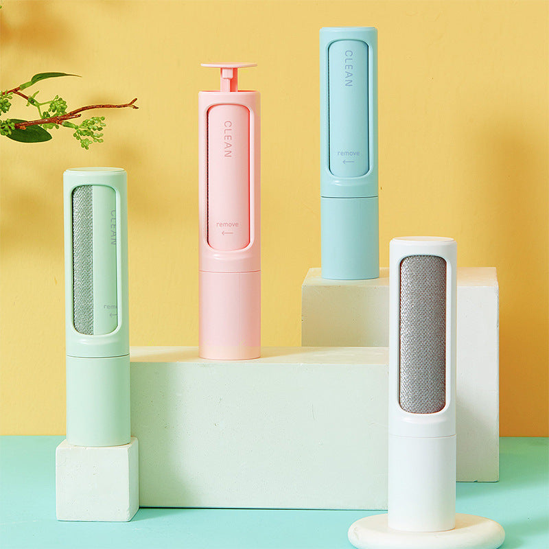 Four pet hair removers in pastel colors on a geometric platform with a yellow and blue gradient background.