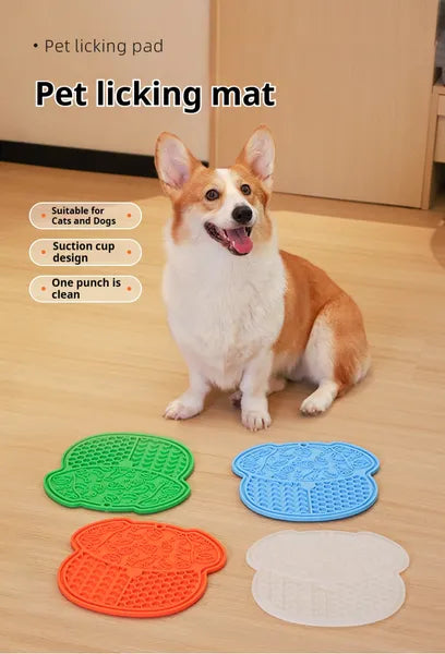 Dog sitting before four pet licking mats displayed on a wooden floor.